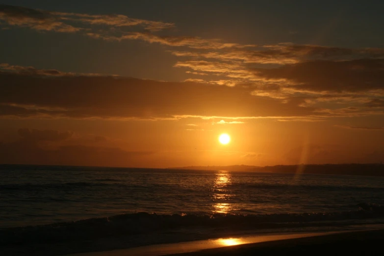 the sun setting over the ocean near a beach