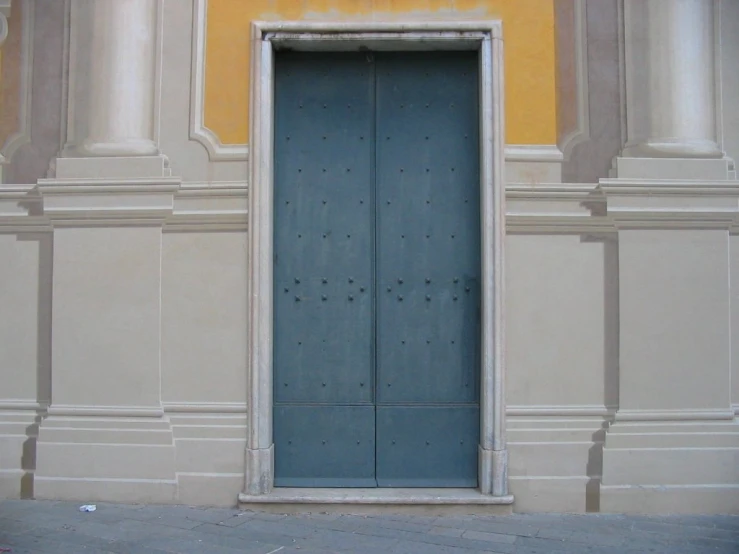 a couple of blue doors next to a yellow wall