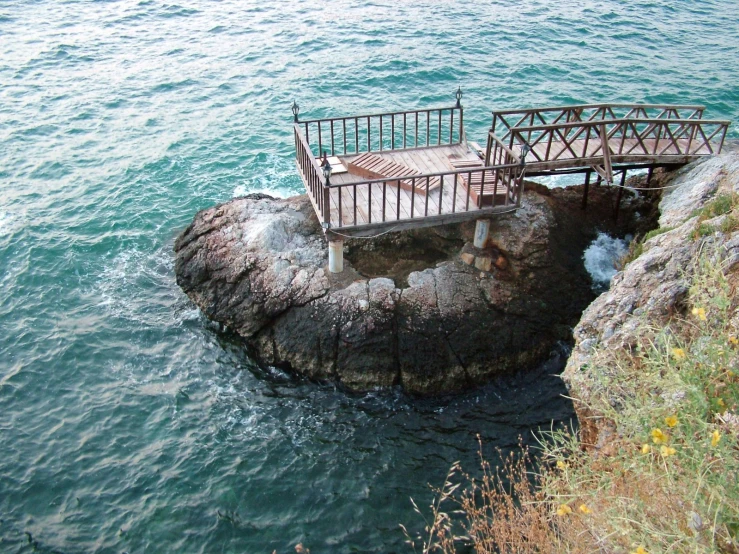 a view from the top of an cliff showing a small bridge over water