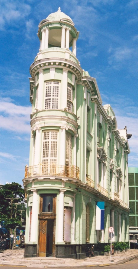 a po of a street corner with an old building and two people walking on the sidewalk in front