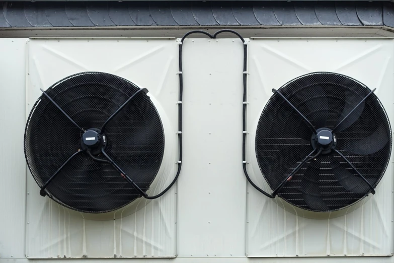 two black fan on top of a white paneled building