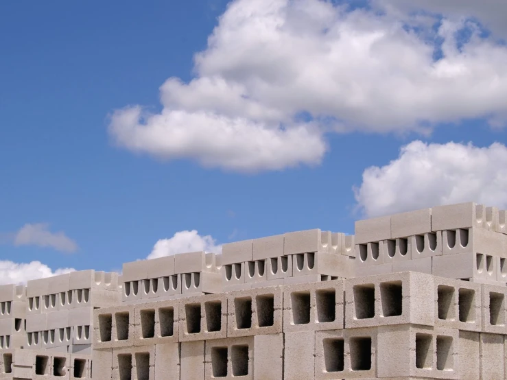 cement block structure with holes and windows against a partly cloudy blue sky