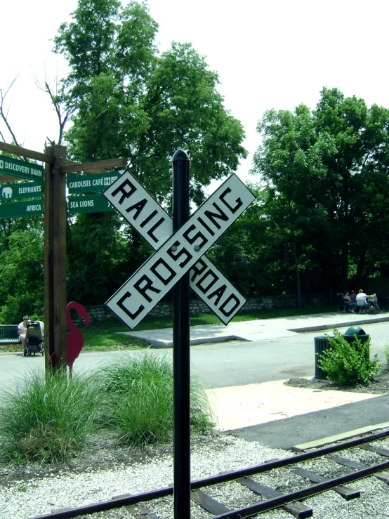 a railroad crossing sign with three street names