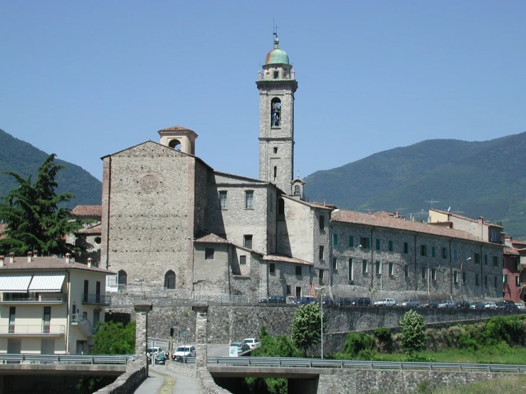 the building with a clock tower sits on a hill top near a walkway