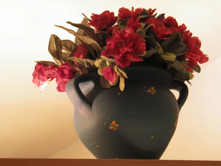 a vase that has red flowers on it