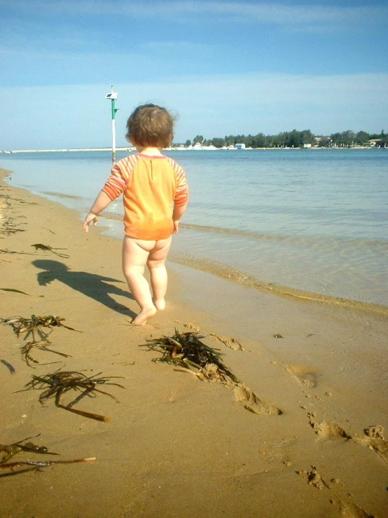 a little boy walking along a beach in the sand
