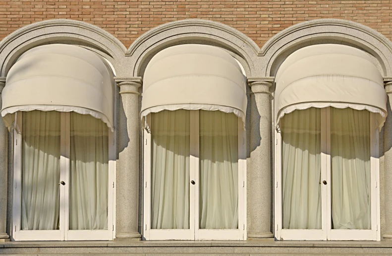 the curved curtains on an arched window are pulled up to reveal ds