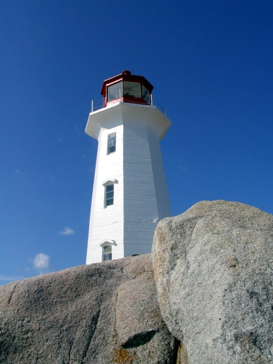 a light house sits on the rocks at the edge of a hill