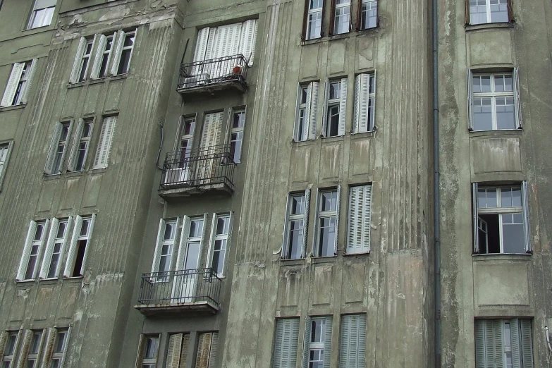 old grey buildings with balconies and broken windows