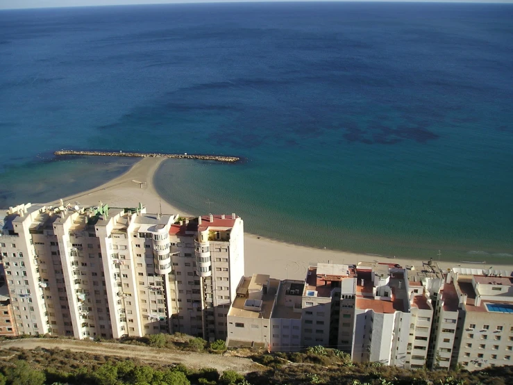 large apartment complex on the ocean with an empty beach