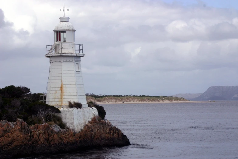 a lighthouse at the shore on a cloudy day