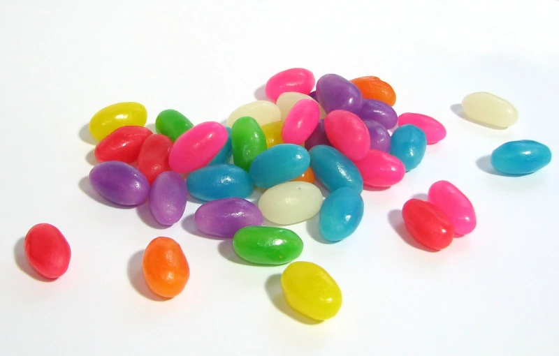 multi colored jelly beans scattered on top of a white surface