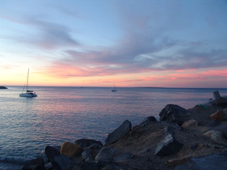 a boat floating in the ocean during sunset