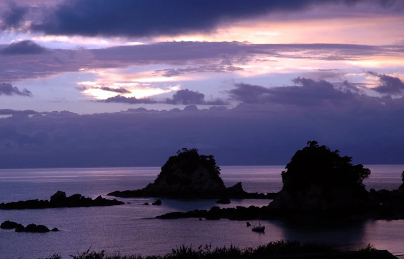 a body of water next to some mountains at dusk