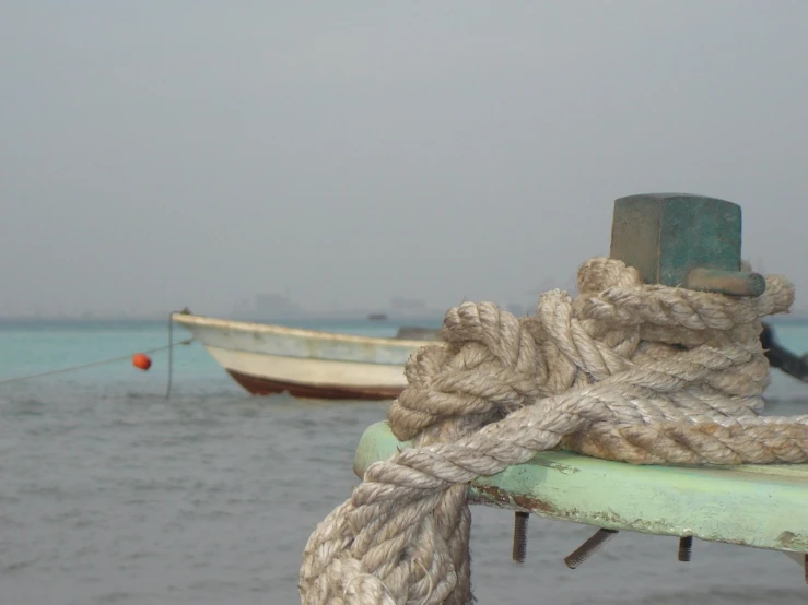 ropes attached to a green boat sitting on the ocean