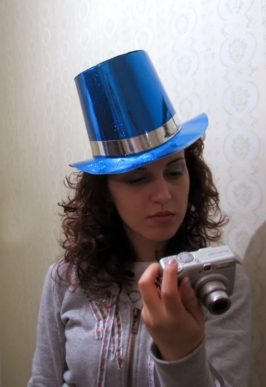 woman with camera taking pograph of large, shiny blue hat