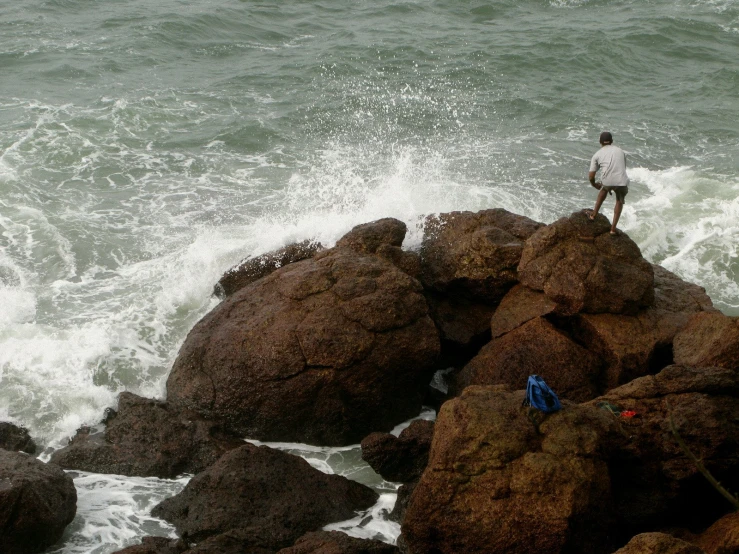 a man stands on rocks overlooking the ocean waves