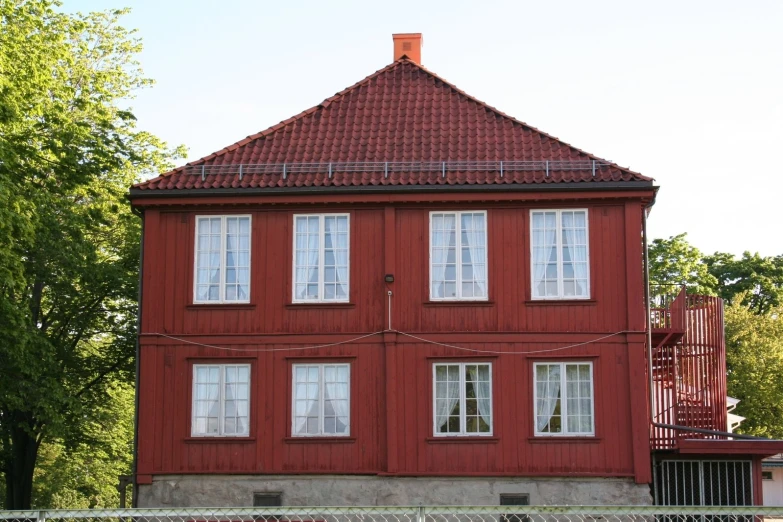 the large red house has white windows near a fence