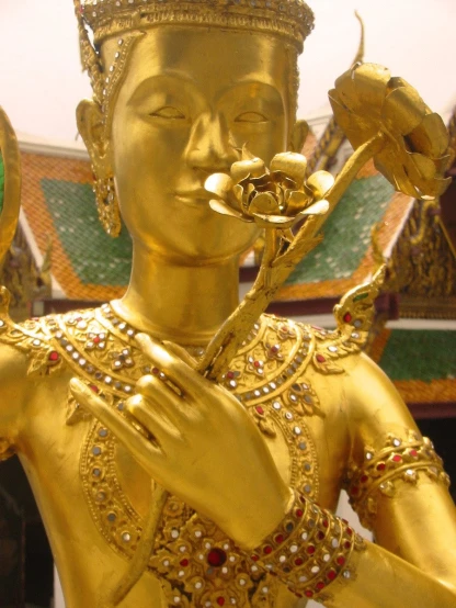a golden statue is holding flowers next to her