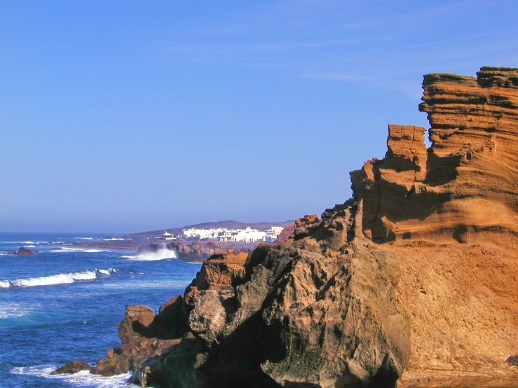 a rocky cliff overlooks the ocean and a beach