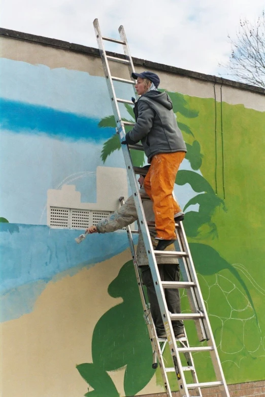 a man painting a large mural with a paint roller