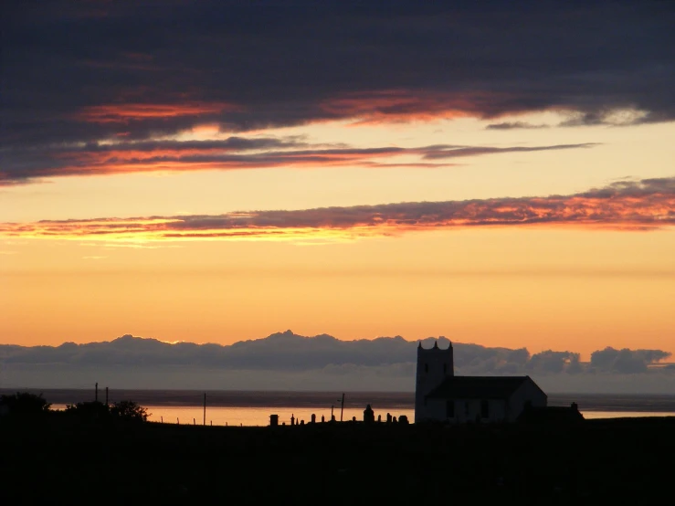 a church is silhouetted against a sunset over the ocean