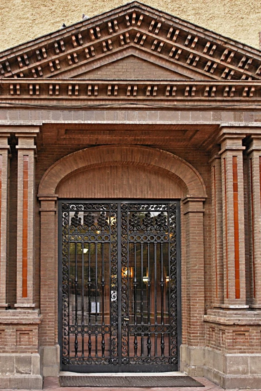 a pair of black wrought - iron doors are opening on an old building