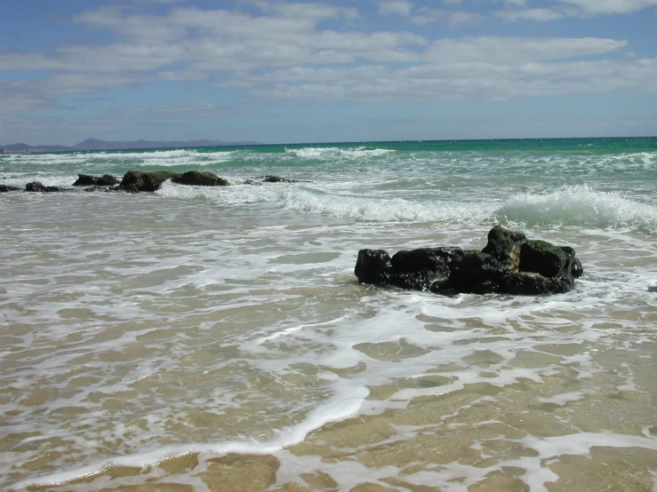 two rocks sticking out from the water with the waves coming in