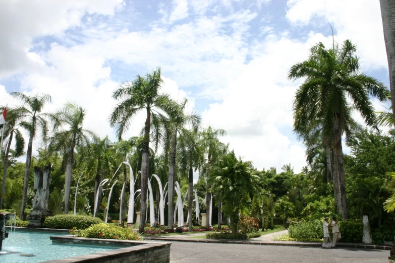 some trees water and statues in the middle of a park