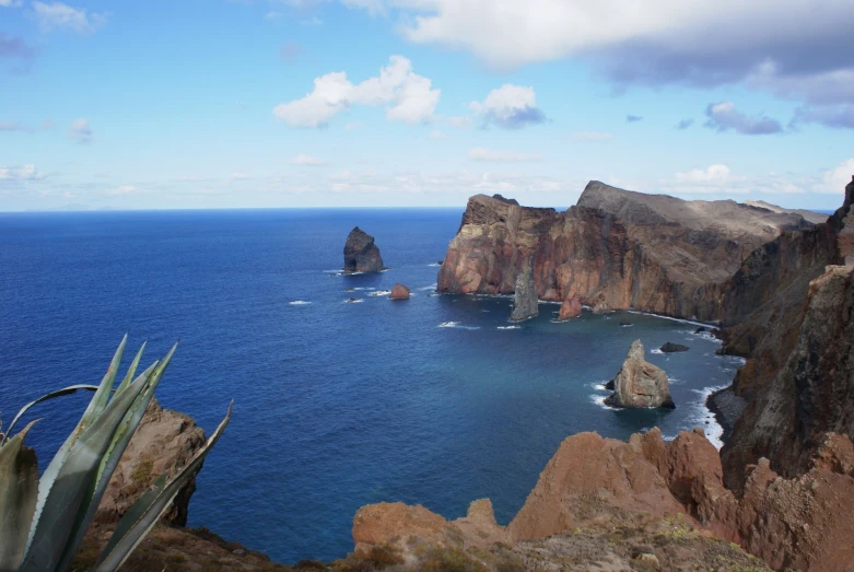 an ocean coastline with a mountain cliff in the foreground