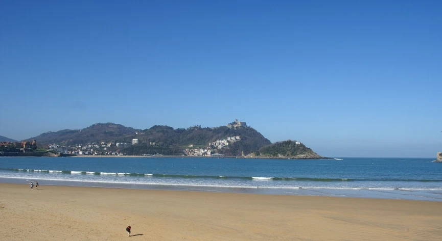 a sandy beach with a few people out at sea