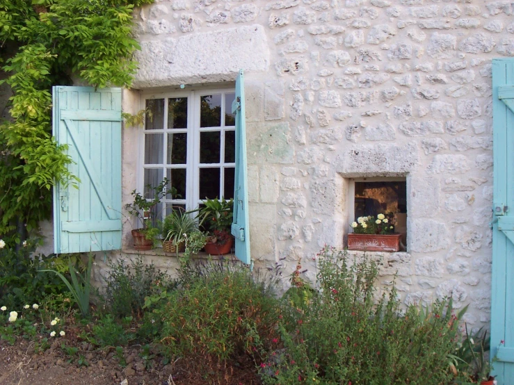 an outside corner of a building with flower pots, flowers and trees in it