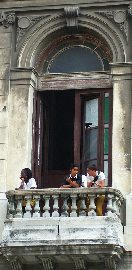 children on balcony in front of old building