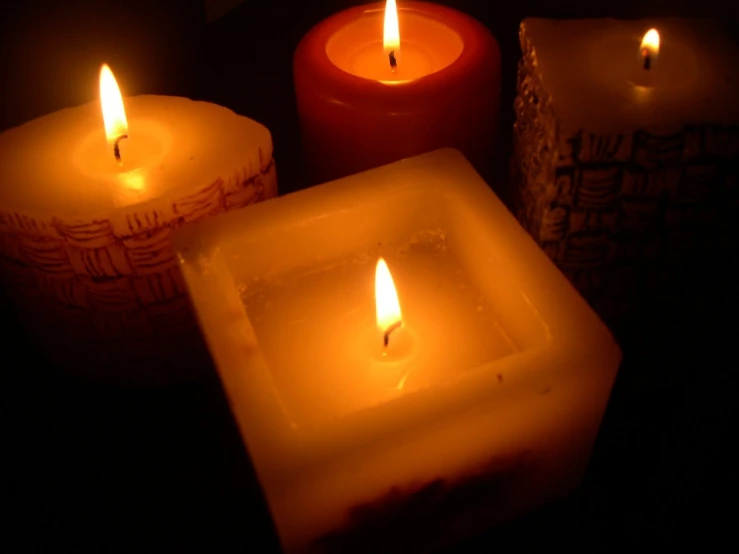 four lit candles, with different shapes and sizes