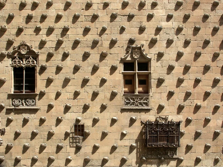 three windows with arched iron bars and railings set in stone