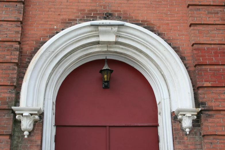 a red door and arch is attached to a brick building