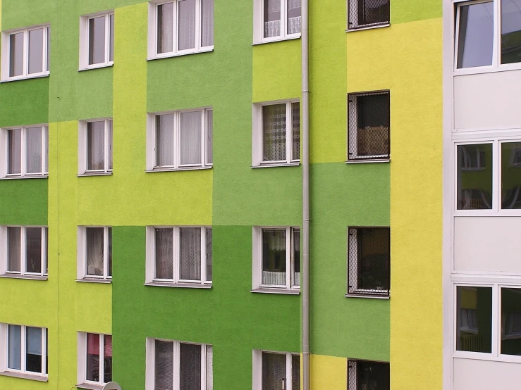 a green building has several white windows and white shutters