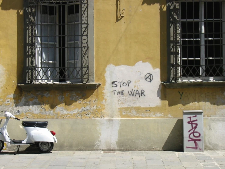 a moped is parked in front of a graffiti - tagged building