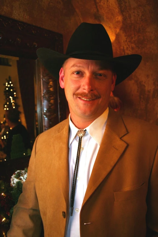 a well - dressed man wearing a black hat is looking at the camera