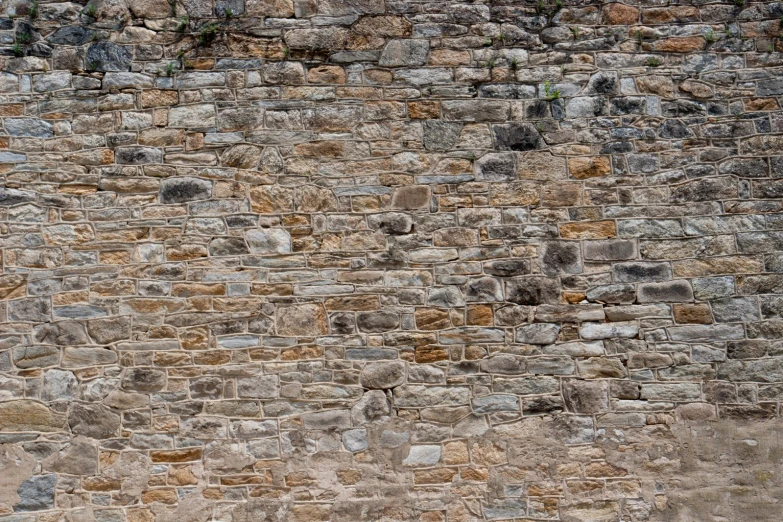 a stop sign stands next to an old stone wall