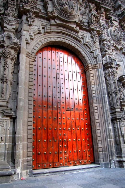 a large red wooden door next to a building