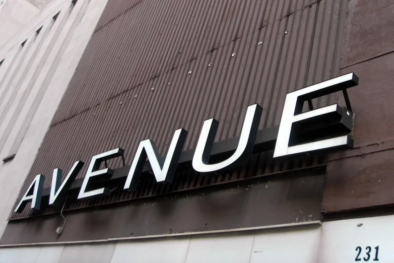 the avenue sign is posted on a tall building