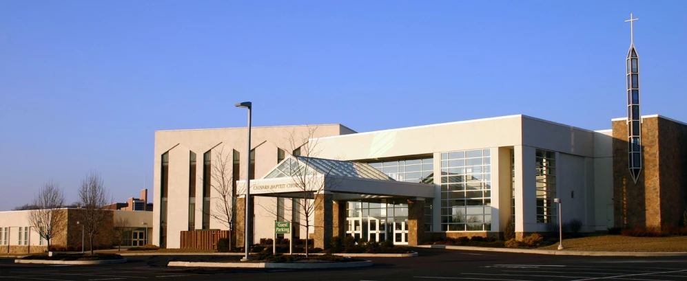 an empty parking lot has cars parked in front of a white building