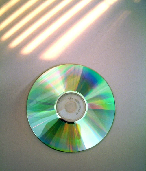 a disc lying on a table with a shadow from the cds