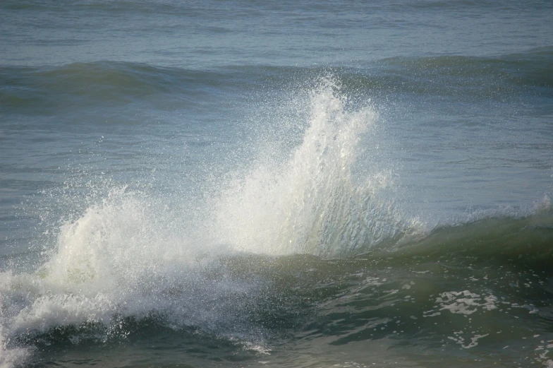 the large wave is crashing against the small rock