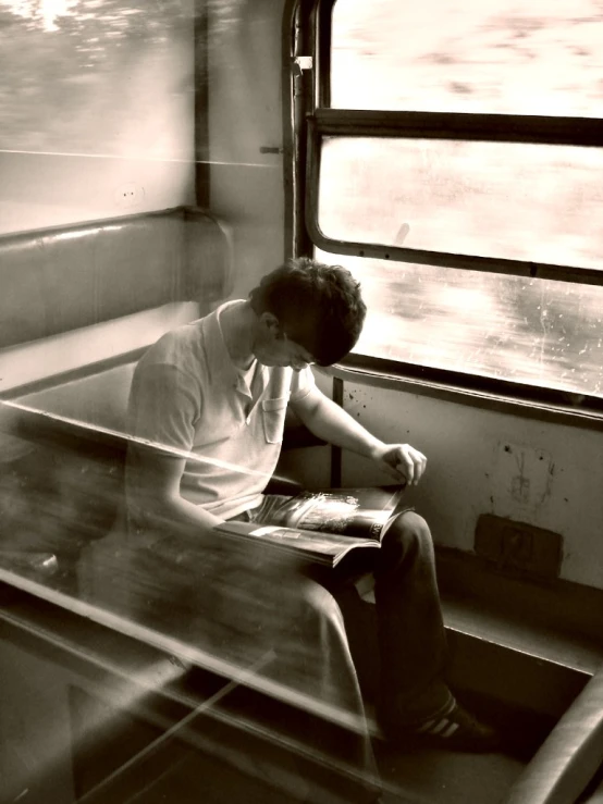 black and white image of a man sitting on a train seat