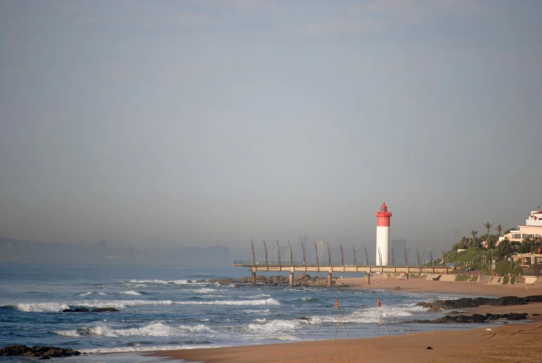 a lighthouse next to the ocean on an overcast day