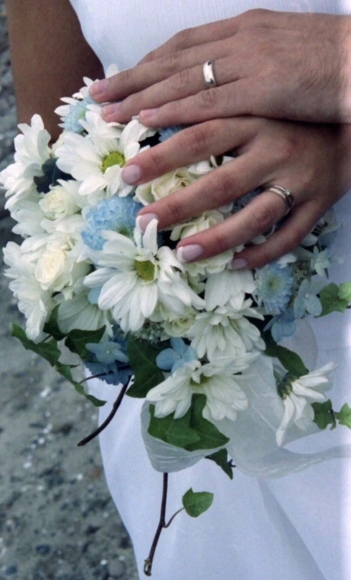 a white wedding bouquet on the brides finger