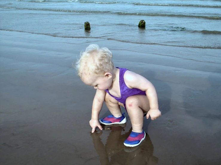 a baby is kneeling on a small beach