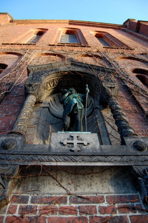 the statue is surrounded by a cross on the side of a building